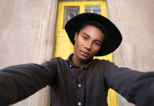 Stylish young African-American man taking selfie outdoors