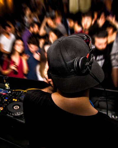 DJ with headphone and dj set at night club party. People at the