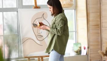 Young female artist painting in workshop