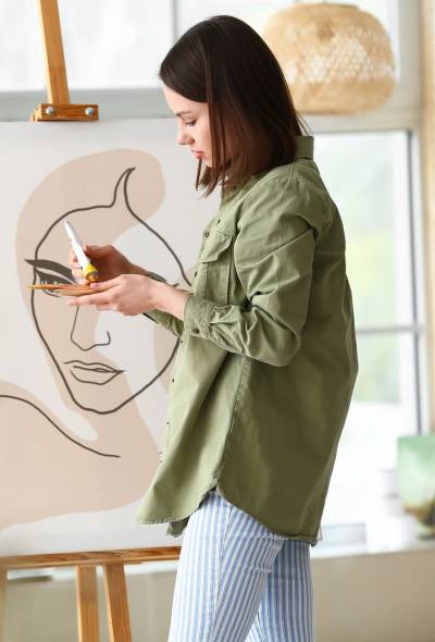 Young female artist painting in workshop