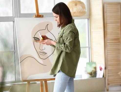 Young female artist painting in workshop