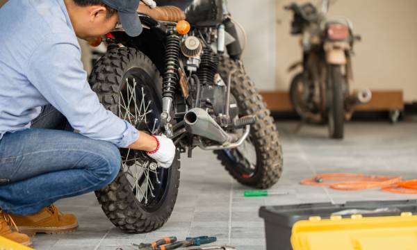 Young man fixing motorcycle in workshop garage, Man repairing motorcycle in repair shop, Mechanical hobby and repairs concepts